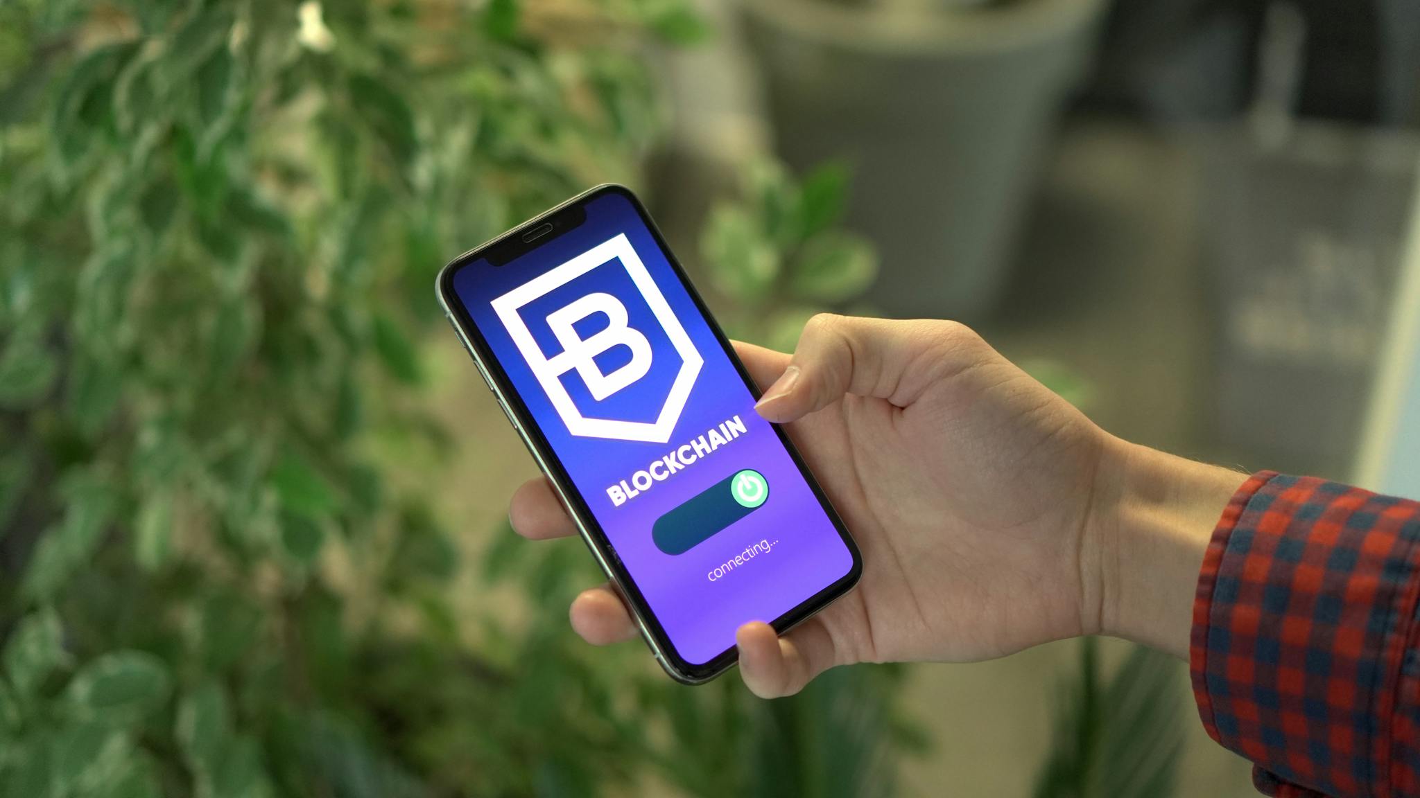 Close-up of a smartphone showing a blockchain app screen held by a hand.